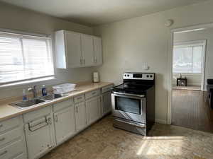 Kitchen with stainless steel electric range oven, light countertops, and white cabinets