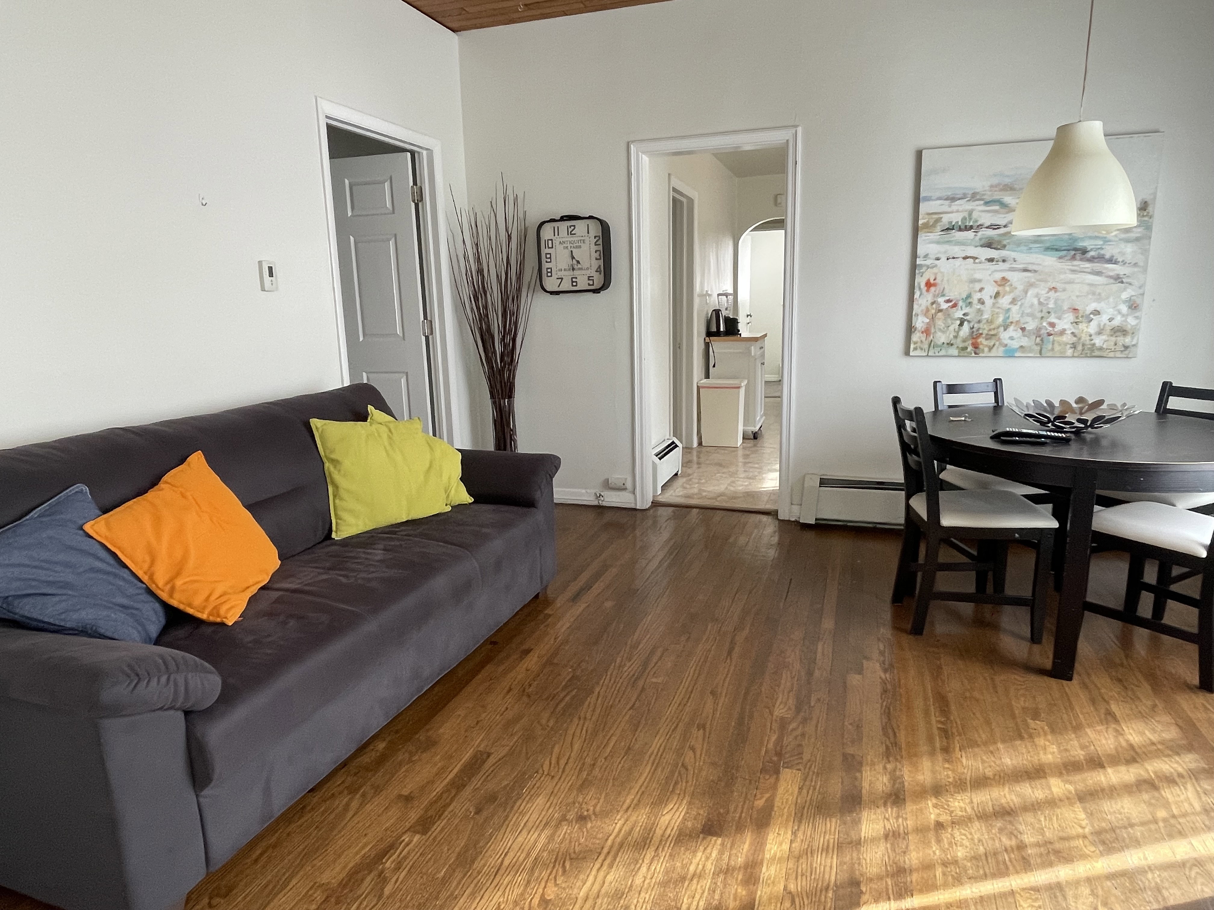 Living room with wood finished floors, a baseboard radiator, and arched walkways