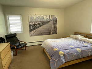 Carpeted bedroom featuring baseboard heating and a textured ceiling