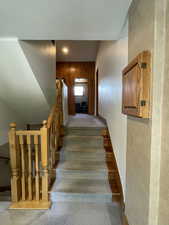 Stairway featuring wood walls, carpet flooring, and a textured wall