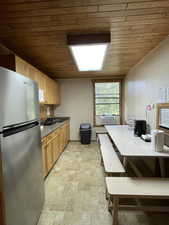 Kitchen featuring freestanding refrigerator, brick patterned flooring, wood ceiling, dark countertops, and cooling unit