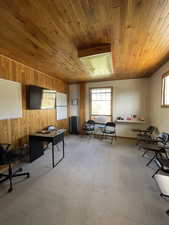Office area featuring light colored carpet, radiator, wooden ceiling, and wood walls