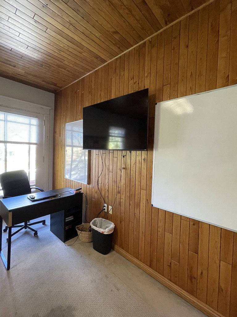 Carpeted home office featuring wooden walls and wooden ceiling