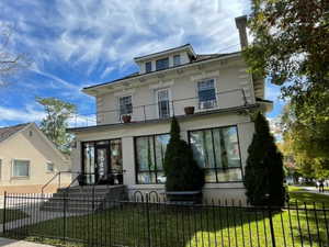 Italianate-style house featuring a fenced front yard and stucco siding
