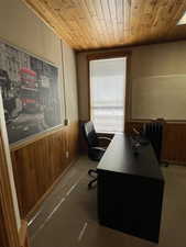 Carpeted office with wooden walls, wainscoting, wooden ceiling, and radiator