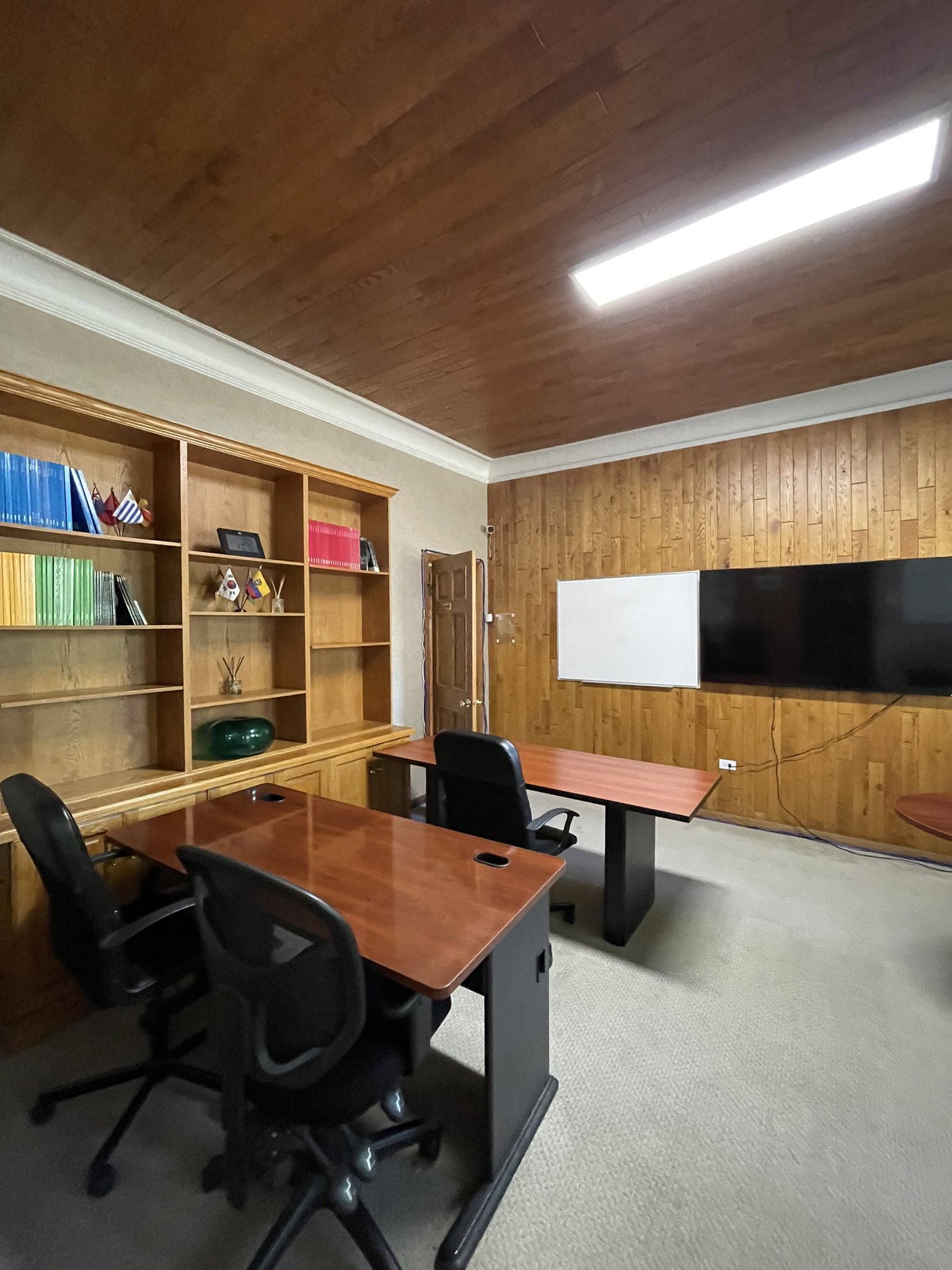 Home office featuring wooden walls, crown molding, and light carpet