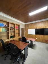 Home office featuring wooden walls, crown molding, and light carpet
