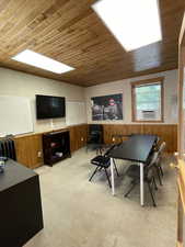 Game room with wooden walls, wainscoting, wood ceiling, radiator, and cooling unit