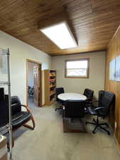 Office with wood walls, light colored carpet, and wooden ceiling
