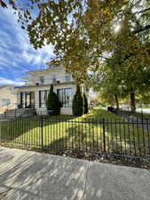 Italianate-style house featuring a fenced front yard, stucco siding, and a patio area