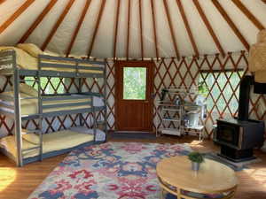 Living room featuring lofted ceiling with beams, wood finished floors, and a wood stove