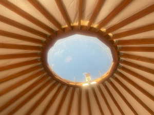 Circular ceiling inside yurt with exposed wooden beams and a central skylight