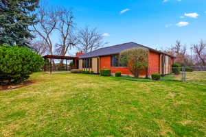 Back of house with a gate, brick siding, and a chimney