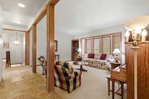 Living room featuring hanging lights, a textured ceiling, and light stone finish floors
