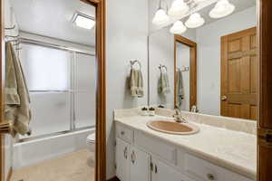 Full bath with vanity and combined bath / shower with glass door