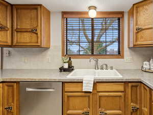 Kitchen featuring stainless steel appliances, wood finish cabinets, light countertops, a textured ceiling, and tasteful backsplash