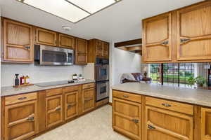 Kitchen featuring wood finish cabinets, light countertops, stainless steel appliances, and light tile patterned floors
