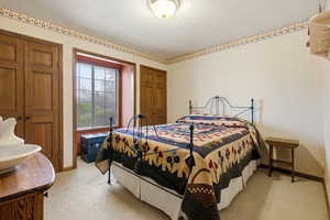 Bedroom with wallpapered walls and light colored carpet
