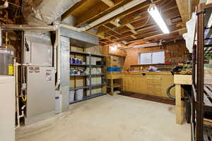Unfinished below grade area featuring water heater, washer / clothes dryer, and a workshop area