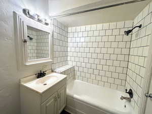 Bathroom featuring vanity, tub / shower combination, and a textured wall
