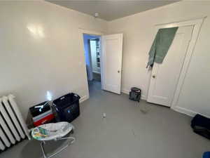 Unfurnished bedroom with radiator and baseboards