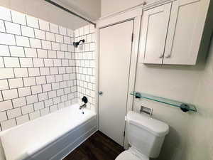 Full bathroom with dark wood finished floors and shower / tub combination