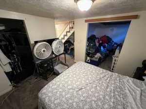 Bedroom with a textured ceiling, dark carpet, and a closet