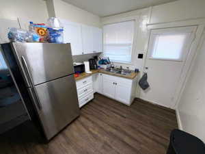 Kitchen featuring freestanding refrigerator, white cabinets, dark wood finished floors, and light countertops