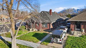 View of front of property featuring a shingled roof, brick siding, and a chimney