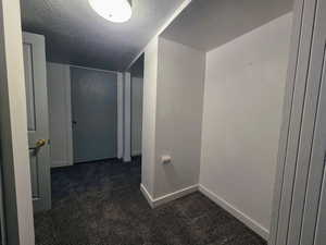 Hall with a textured ceiling and dark carpet