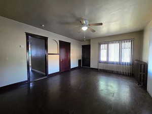 Unfurnished bedroom with ceiling fan and radiator heating unit