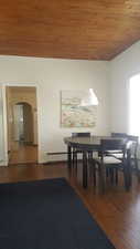 Dining space featuring wooden ceiling, dark wood finished floors, and arched walkways