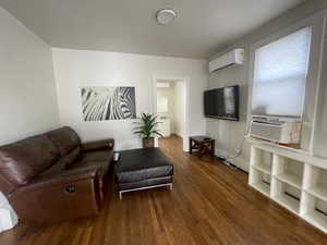 Living room featuring dark wood-style flooring, a wall mounted mini split, and cooling unit