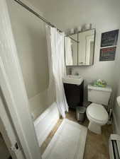 Full bath featuring vanity, shower / bath combination with curtain, light tile patterned floors, and a baseboard radiator