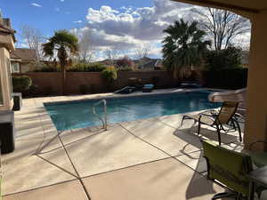 View of swimming pool featuring patio surround, a fenced backyard, and a water slide