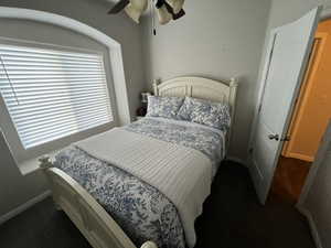 Bedroom with a ceiling fan and dark carpet