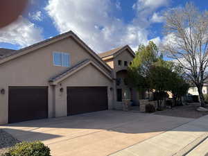 Traditional home with driveway, an attached garage, stucco siding, and a tiled roof