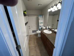 Full bath with vanity, shower / bath combination with curtain, and dark tile patterned flooring