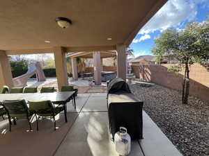 Fenced backyard featuring outdoor dining area, a patio area, and a hot tub