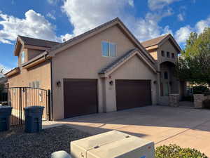 Traditional home with a garage, concrete driveway, stucco siding, and a tiled roof