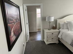 Bedroom with dark colored carpet and baseboards