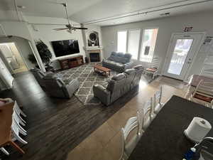 Living area featuring tile patterned floors, ceiling fan, arched walkways, vaulted ceiling, and a fireplace