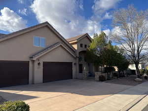 View of front of house with driveway, stucco siding, an attached garage, and a tiled roof