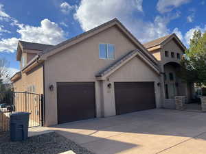 View of front of home featuring a garage, stucco siding, driveway, and a gate