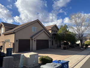 Traditional-style home featuring stucco siding, concrete driveway, an attached garage, and a tile roof