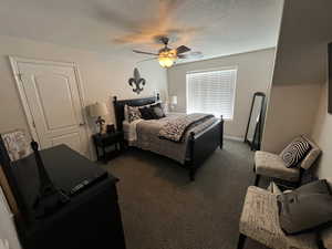 Bedroom featuring dark carpet, ceiling fan, and a textured ceiling