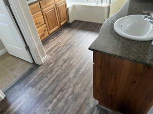 Bathroom view of vanity, a bath, and wood finished floors