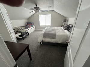 Bedroom with dark carpet, a textured ceiling, and a ceiling fan