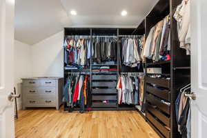 Walk in closet featuring light wood-style floors and vaulted ceiling