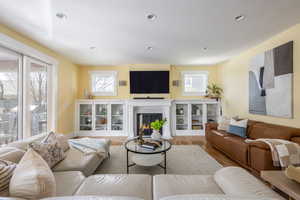 Living room with light wood-style floors, a fireplace with flush hearth, and recessed lighting